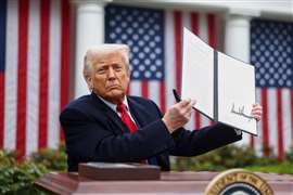 US president Donald Trump holds up a signed executive order with the stars and strips flags behind him